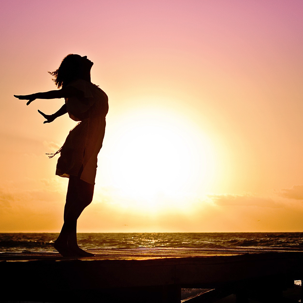 donna con braccia alzate al mare tramonto